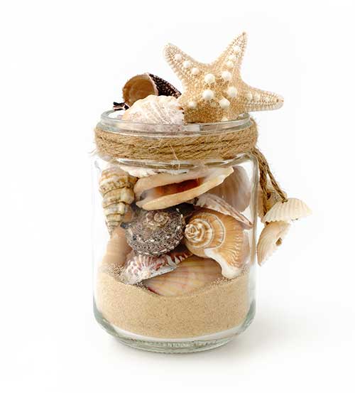 glass jar with sand and seashells in it