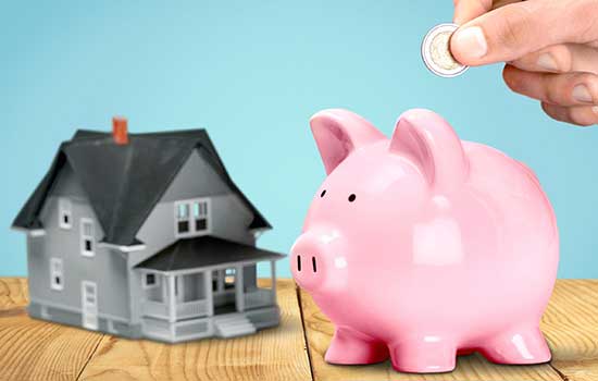 model of house with a piggy bank next to it and coins