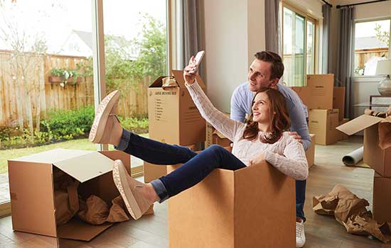 man and woman taking a selfie amongst moving boxes