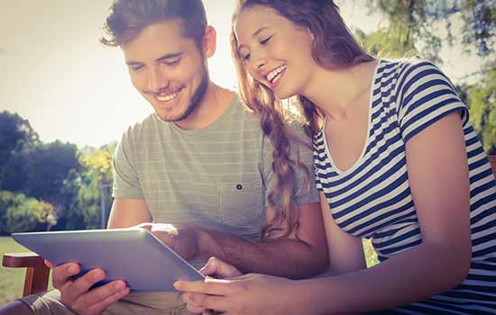 man and woman sitting outside looking at tablet