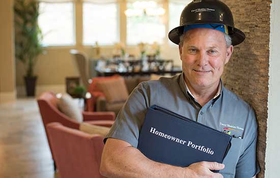 man wearing David Weekley Homes shirt and hard hat holding a David Weekley Homeowners Portfolio