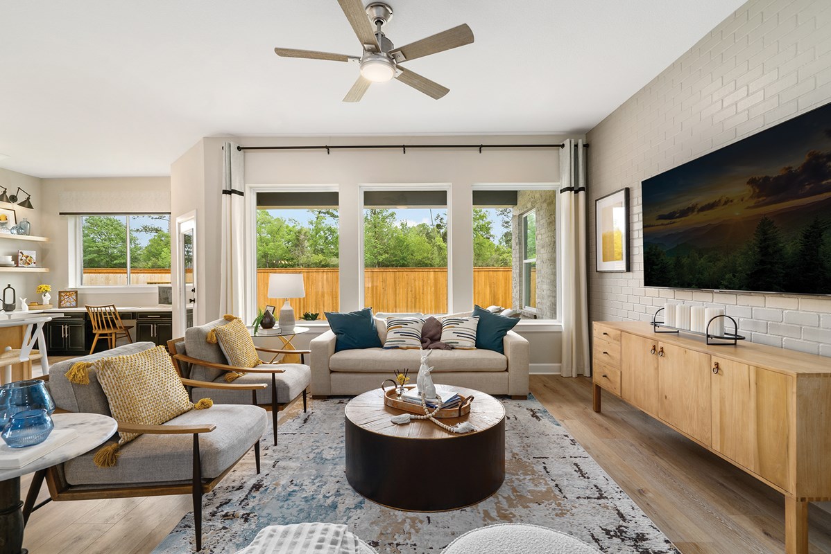 This David Weekley model home’s Family Room features a neutral color palette, upholstered seating, mixed wood furniture, and layers of color through precise use of accessories, including throw pillows and decorative touches on the tables.