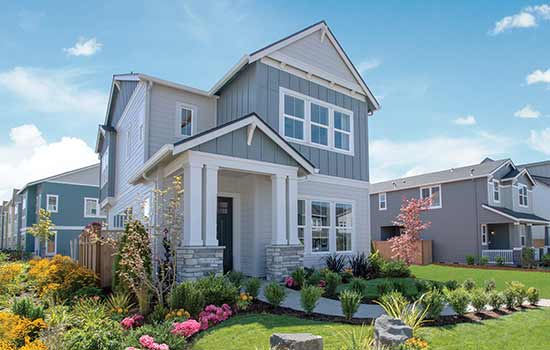 The exterior of The Coleton model home by David Weekley Homes. A manicured lawn and blooming garden rest in front of a two-story home with a covered front porch.