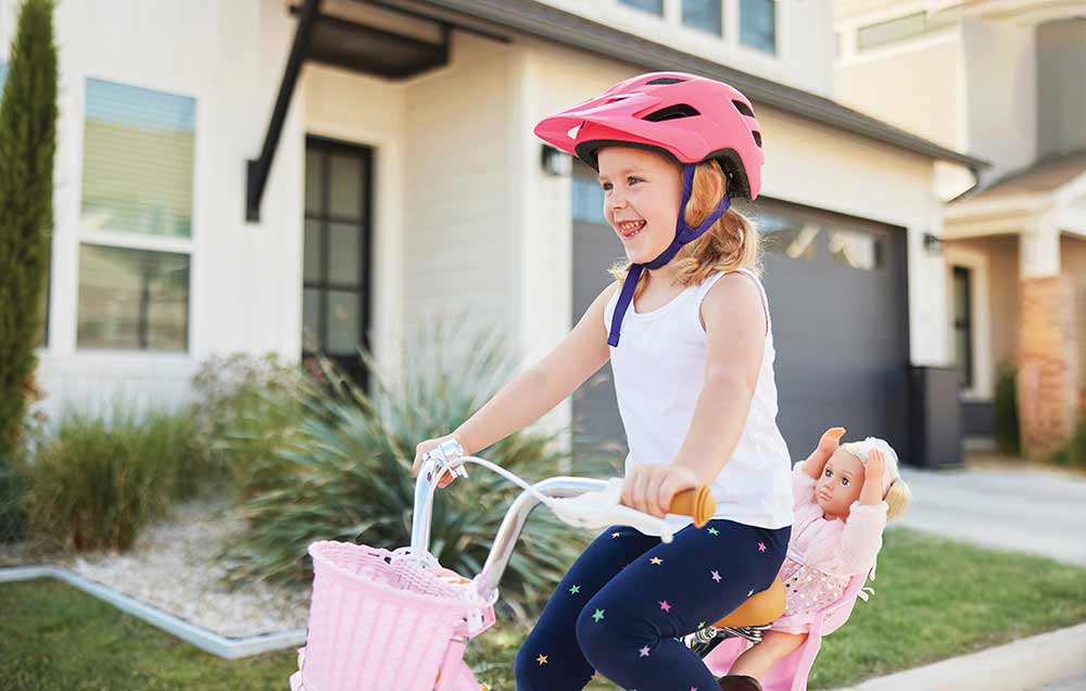 A young girl is bike on the sidewalk in front of a home