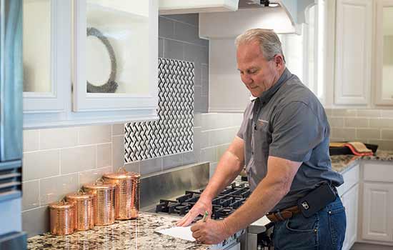 A David Weekley Homes Team Member takes notes on a sheet of paper in a beautifully apppointed model home kitchen.