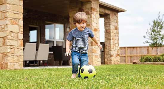 child playing with soccer ball in large yard