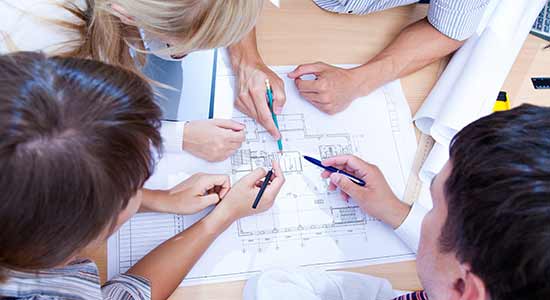group of people looking at a blue print of a floor plan