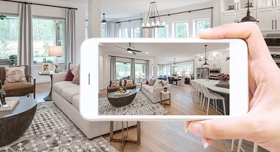 hand holding mobile phone with photo of living room on it