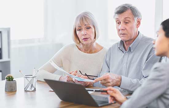 a man and woman talking with another woman and looking at a laptop screen