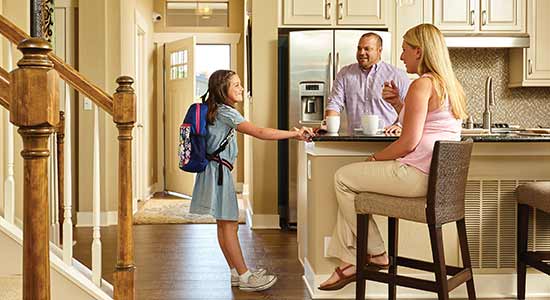 man and woman standing at kitchen counter talking to young girl