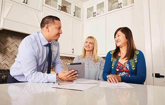 three people standing around kitchen counter smiling at each other