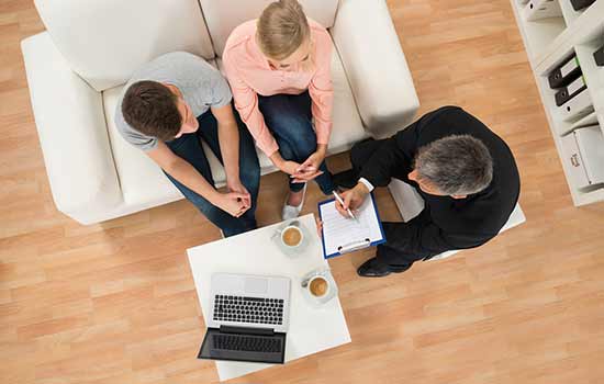 overhead view of three people sitting in chairs looking at a laptop