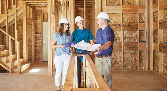 man and woman talking to builder in partially constructed home