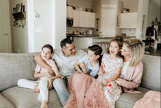 young family with children sitting on a couch and laughing