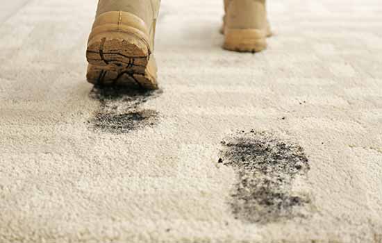 muddy boots tracking in footprints on carpet