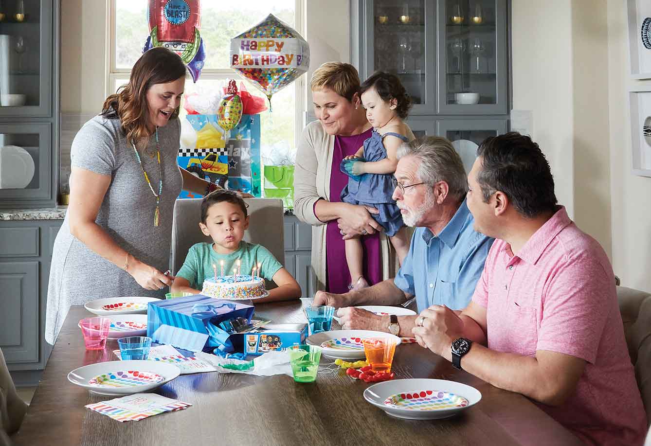 Three generations of a family enjoying a birthday celebration in a beautiful David Weekley Home.