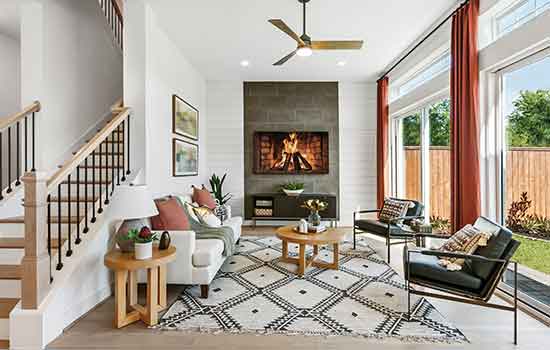 A beautiful David Weekley model home’s Family Room with a few throw pillows on the furniture and potted plants on the tables.