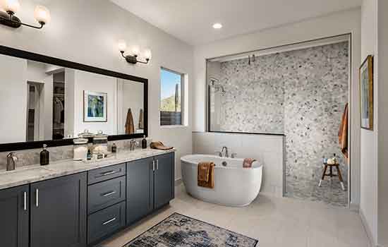 A beautiful David Weekley model home’s Owner’s Bath with only a few products visible on the countertops and by the tub and shower.