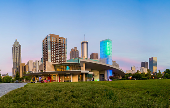 A photograph of the Coca-Cola Museum with the Downtown Atlanta skyline visible in the background