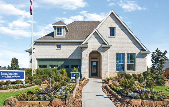 A beautiful David Weekley model home in Magnolia, Texas, with a garden-lined walkway up to the front door.