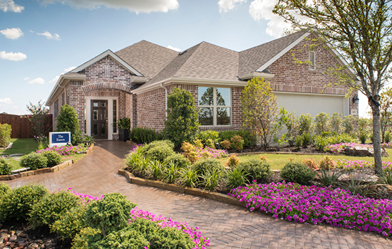 A beautiful David Weekley model home in Forney, Texas, with a garden-lined walkway up to the front door.