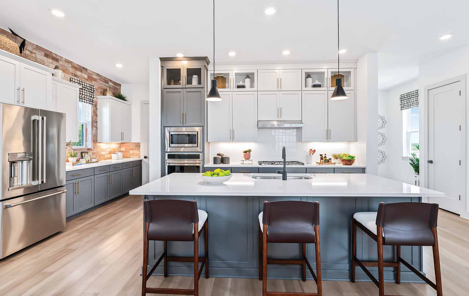 Long wood floor tiles visually extend the space of this kitchen, where a dark blue island and lower cabinetry is paired with white quartz countertops, white subway tile backsplash, and white cabinets.