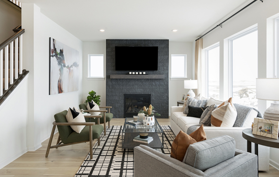 A family room in a model home, featuring furniture and a black fireplace with a TV mounted above the mantlepiece, similar to the home you could live in when you relocate to Rosemount, MN