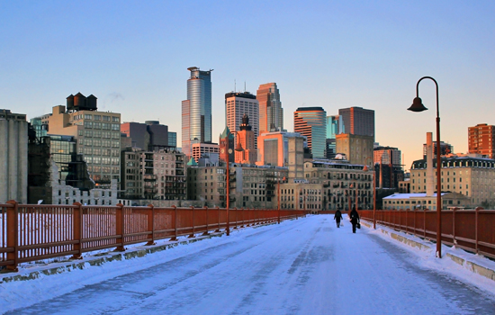 Snow covers a bridge leading to Downtown Minneapolis at dawn