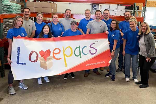 David Weekley Homes Team Members posing with a sign from LOVEPACS