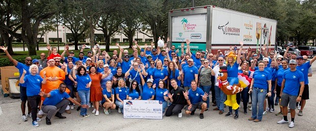 David Weekley Homes Team Members posing with a large check and a large truck with donated food