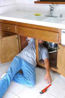 Man under a sink with wrench.